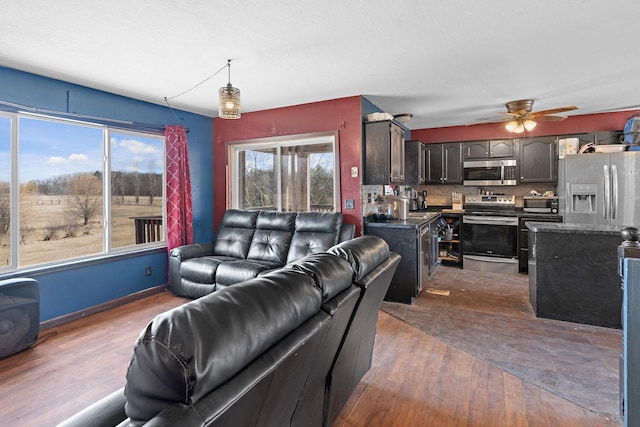 living room featuring ceiling fan, baseboards, and dark wood-type flooring