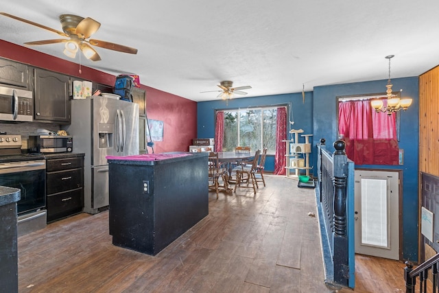 kitchen with appliances with stainless steel finishes, dark wood finished floors, and ceiling fan with notable chandelier