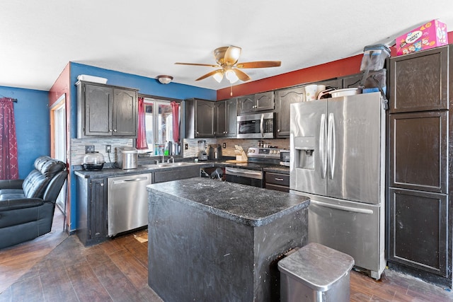 kitchen with dark wood-style flooring, dark countertops, a ceiling fan, backsplash, and stainless steel appliances