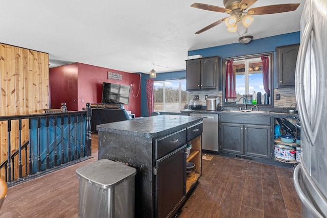 kitchen featuring a sink, appliances with stainless steel finishes, dark wood-style floors, and dark countertops