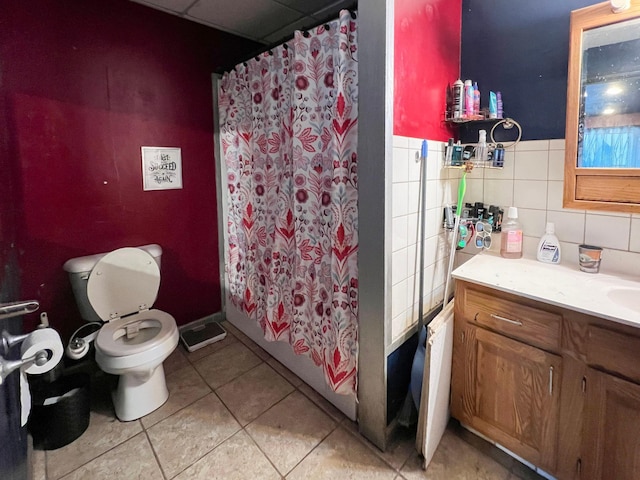 full bathroom with toilet, tile patterned floors, tile walls, and vanity