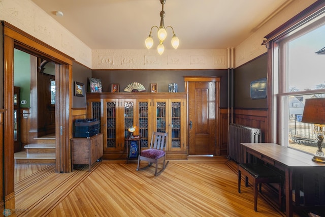 entrance foyer featuring french doors, a wainscoted wall, radiator, and wood finished floors