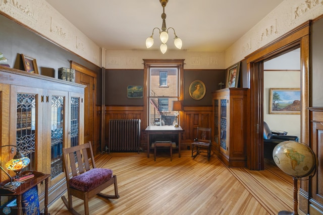 sitting room featuring radiator, wood finished floors, and a chandelier