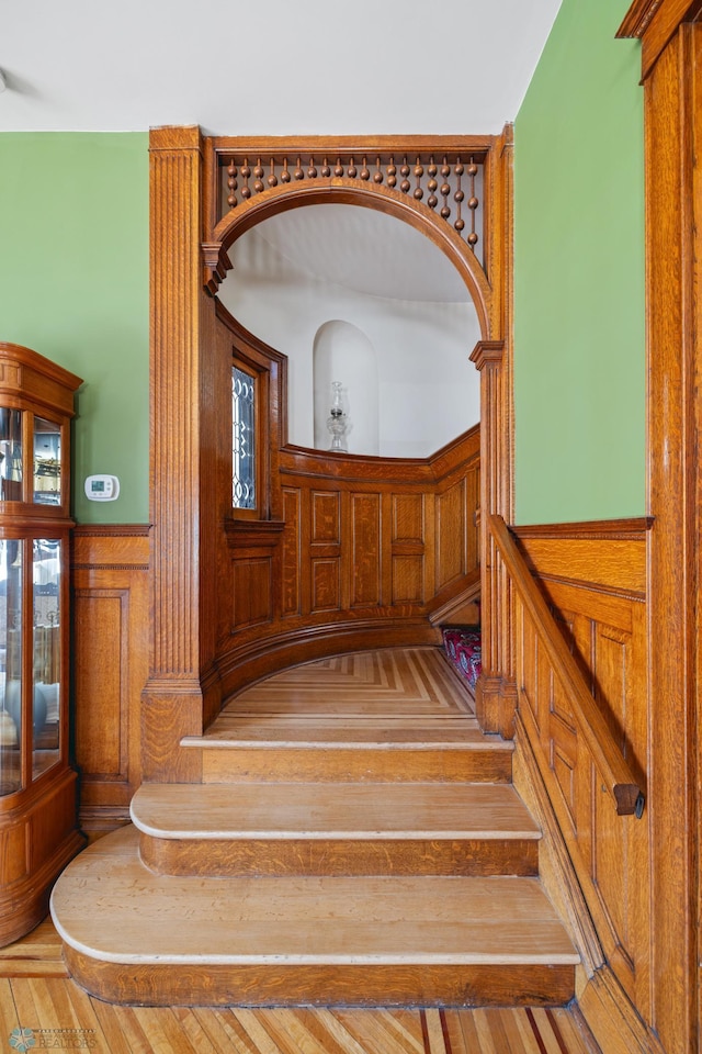 stairway with wainscoting and hardwood / wood-style flooring