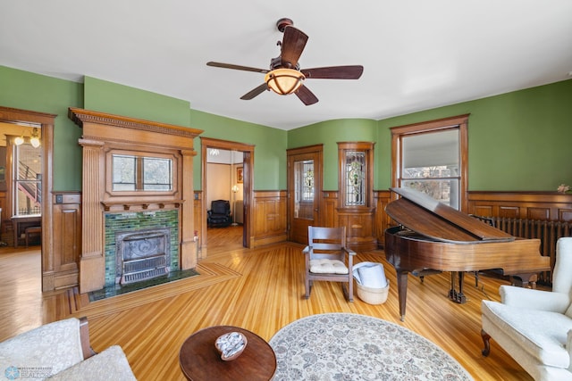 living room featuring a ceiling fan, a wainscoted wall, radiator, and wood finished floors