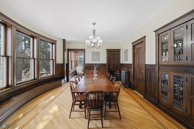 dining room with light wood finished floors, wainscoting, and a chandelier