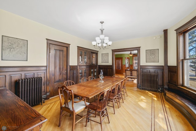 dining area with radiator heating unit, wainscoting, and light wood-type flooring