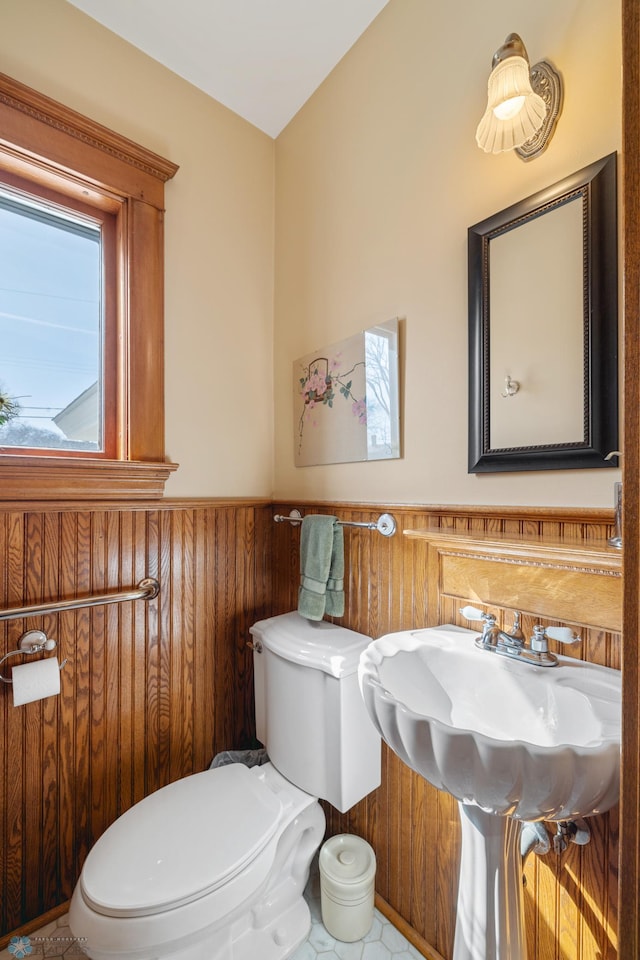 half bath with toilet, wainscoting, and wood walls