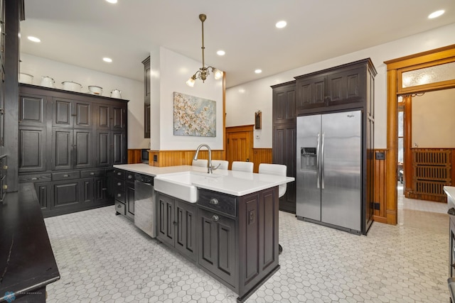 kitchen with light countertops, recessed lighting, a wainscoted wall, a sink, and appliances with stainless steel finishes