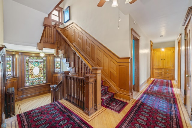 stairs featuring a towering ceiling, wood finished floors, and ceiling fan