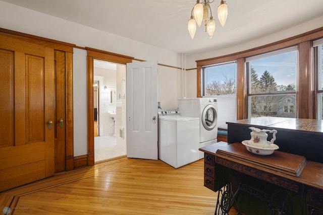 laundry area with separate washer and dryer, light wood-type flooring, and a chandelier
