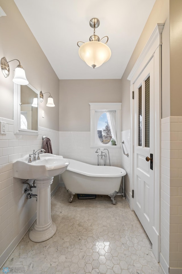 full bath with tile walls, a wainscoted wall, and a soaking tub