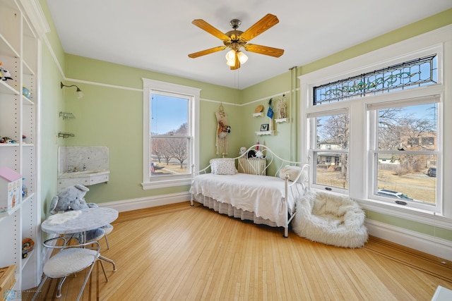 bedroom with baseboards, wood finished floors, and multiple windows