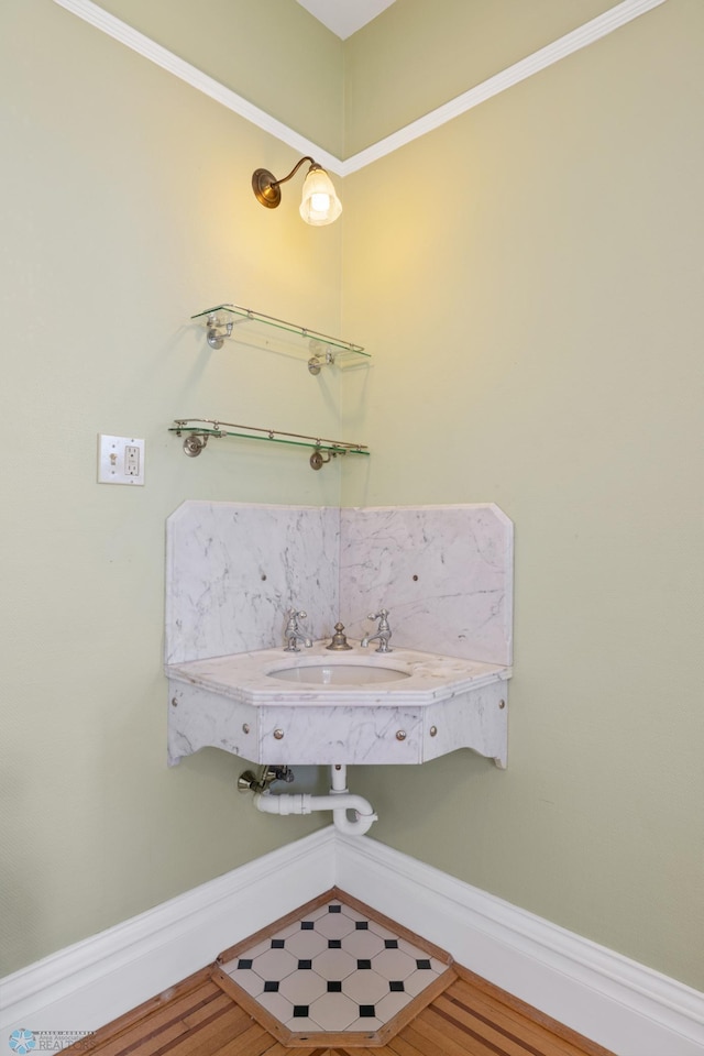 bathroom featuring baseboards, wood finished floors, and a sink