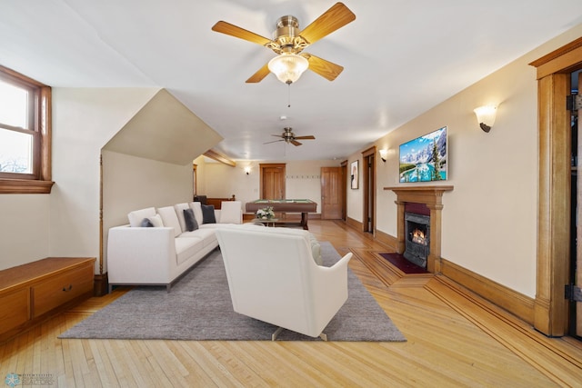 living area with a warm lit fireplace, light wood-style flooring, billiards, and baseboards