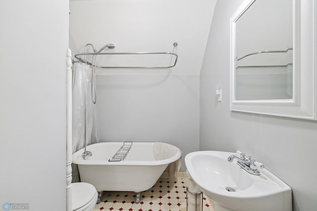 bathroom featuring toilet, a sink, and a freestanding tub