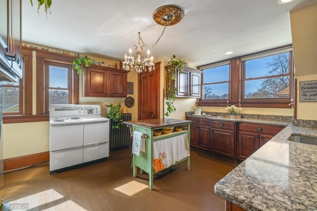 kitchen featuring dark wood-style flooring, stone countertops, an inviting chandelier, and range with two ovens