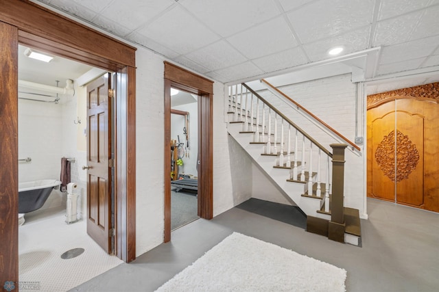 finished basement featuring stairs and a paneled ceiling