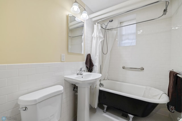 bathroom featuring shower / tub combo, tile walls, toilet, a wainscoted wall, and tile patterned floors