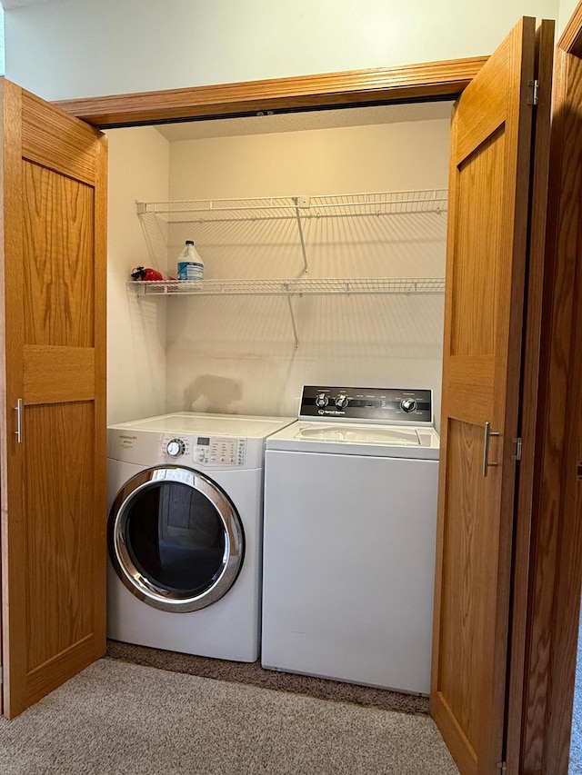 clothes washing area featuring washing machine and dryer, light colored carpet, and laundry area