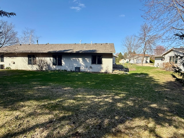 view of side of property featuring a lawn, roof with shingles, and central AC