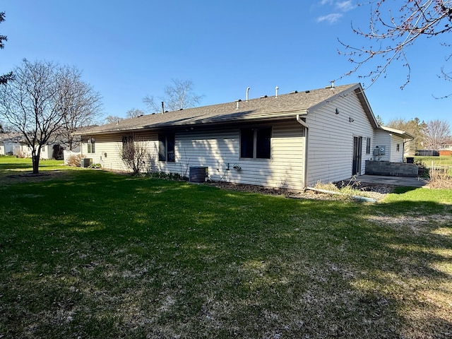 rear view of property featuring central air condition unit and a lawn