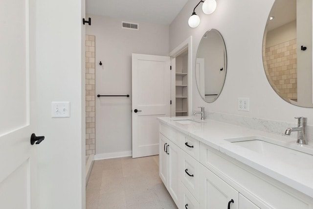 full bath featuring double vanity, a sink, baseboards, and visible vents