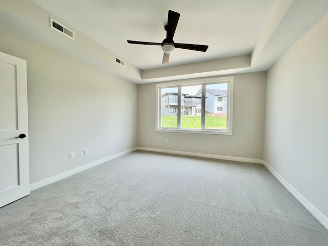 empty room with carpet floors, baseboards, ceiling fan, and visible vents