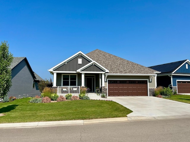 craftsman-style home featuring a front yard, stone siding, board and batten siding, a garage, and a porch