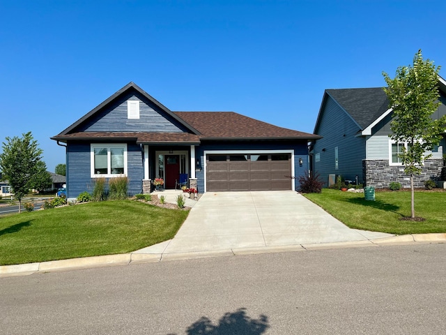 craftsman house featuring a front yard, concrete driveway, roof with shingles, and an attached garage