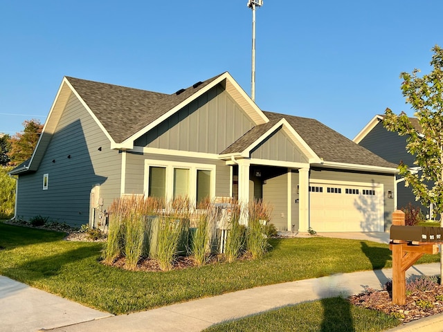craftsman inspired home featuring a shingled roof, a front yard, an attached garage, and board and batten siding