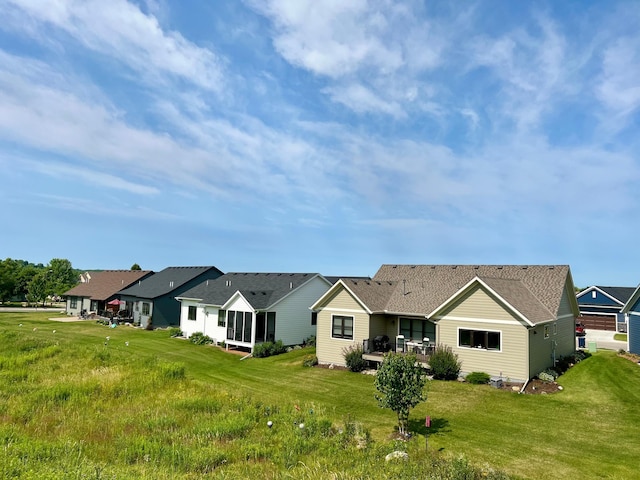 rear view of property featuring a shingled roof and a lawn