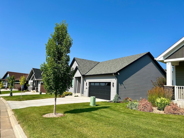 view of front of house with driveway, a shingled roof, a garage, and a front yard