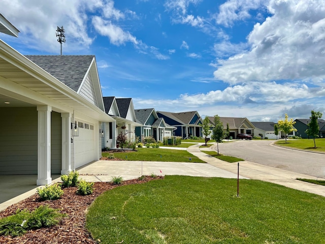 view of yard featuring a residential view, driveway, and an attached garage
