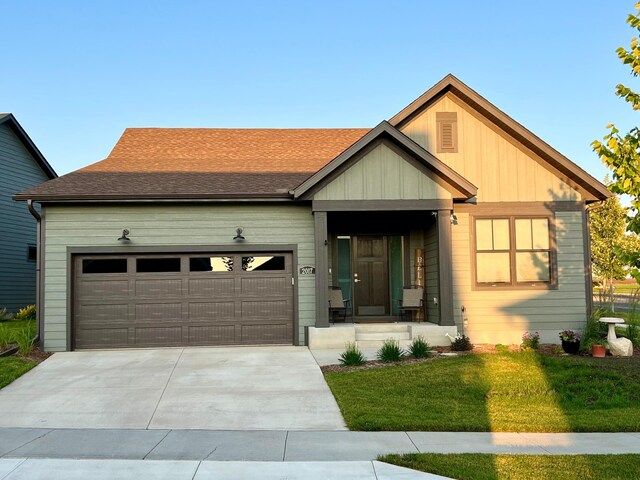 view of front of property featuring driveway, a shingled roof, a garage, and a front lawn