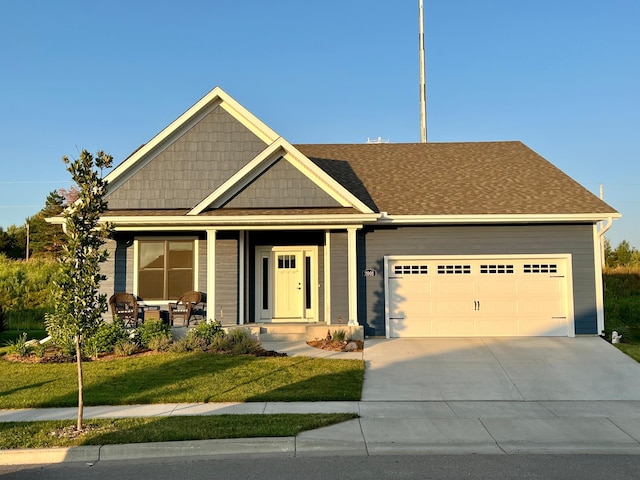 craftsman-style home featuring a garage, a front lawn, roof with shingles, driveway, and covered porch