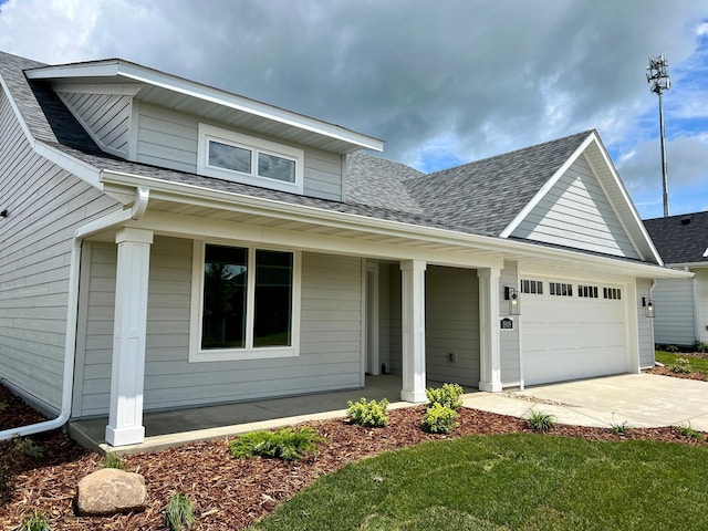 view of front of house with driveway, a shingled roof, covered porch, and an attached garage