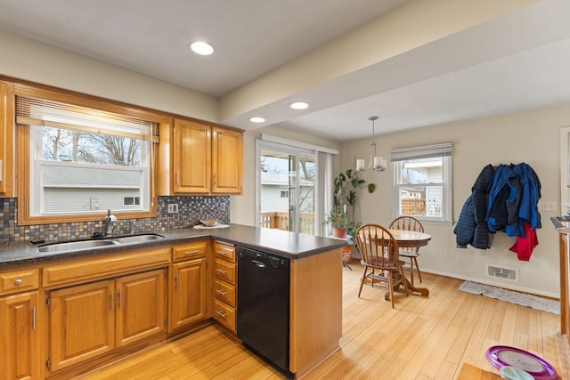 kitchen with black dishwasher, dark countertops, a sink, visible vents, and a peninsula
