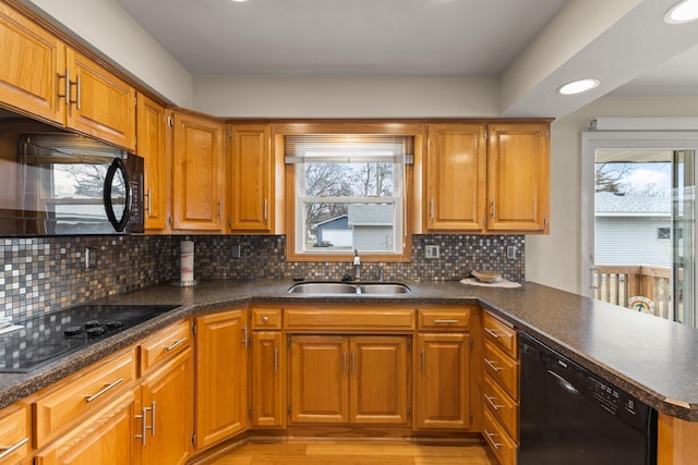 kitchen featuring black appliances, a sink, a peninsula, and dark countertops