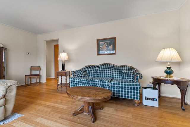 living room with baseboards, light wood-type flooring, and ornamental molding