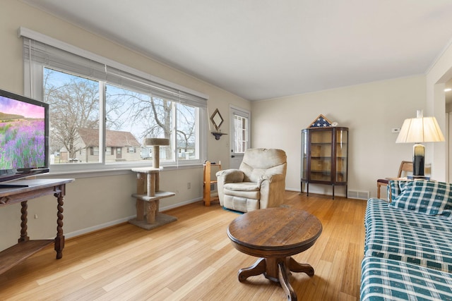 living room with wood finished floors, visible vents, and baseboards