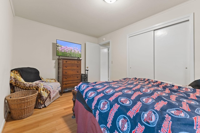 bedroom with wood finished floors, ornamental molding, and a closet