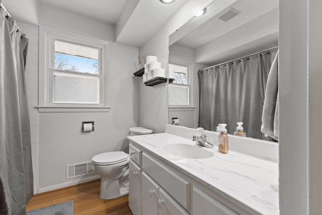 bathroom with wood finished floors, visible vents, and a healthy amount of sunlight