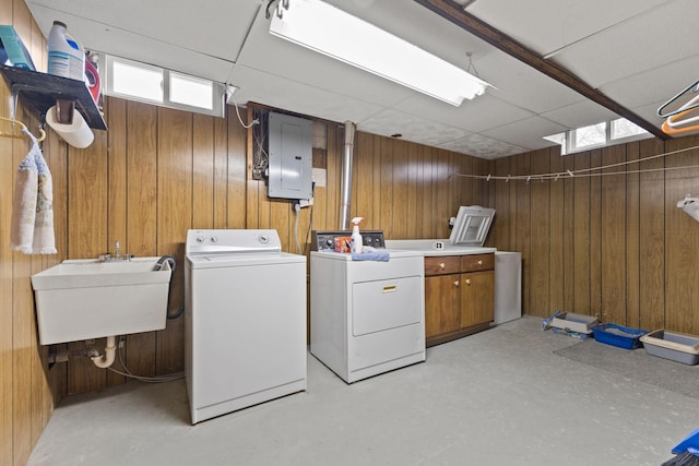 laundry area featuring a sink, cabinet space, washing machine and dryer, electric panel, and wooden walls