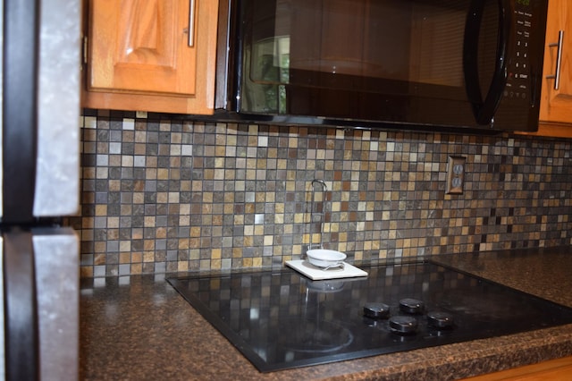 details featuring black appliances, dark countertops, and backsplash