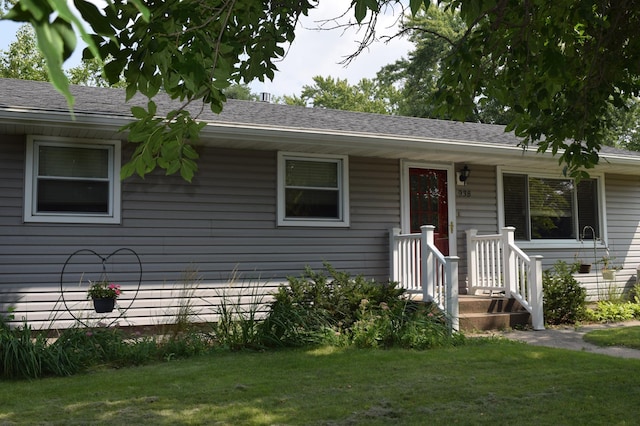 ranch-style house featuring a shingled roof and a front yard
