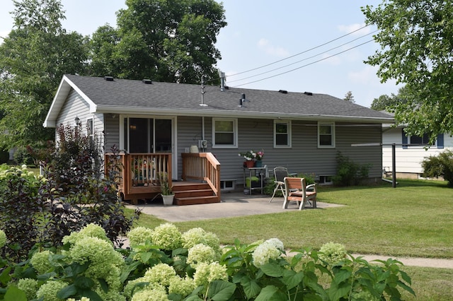 rear view of house with roof with shingles, a yard, a wooden deck, and a patio area