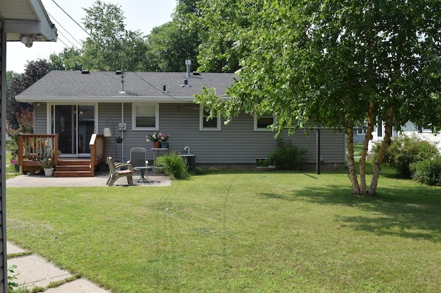 back of house featuring a shingled roof, central air condition unit, a wooden deck, a patio area, and a lawn