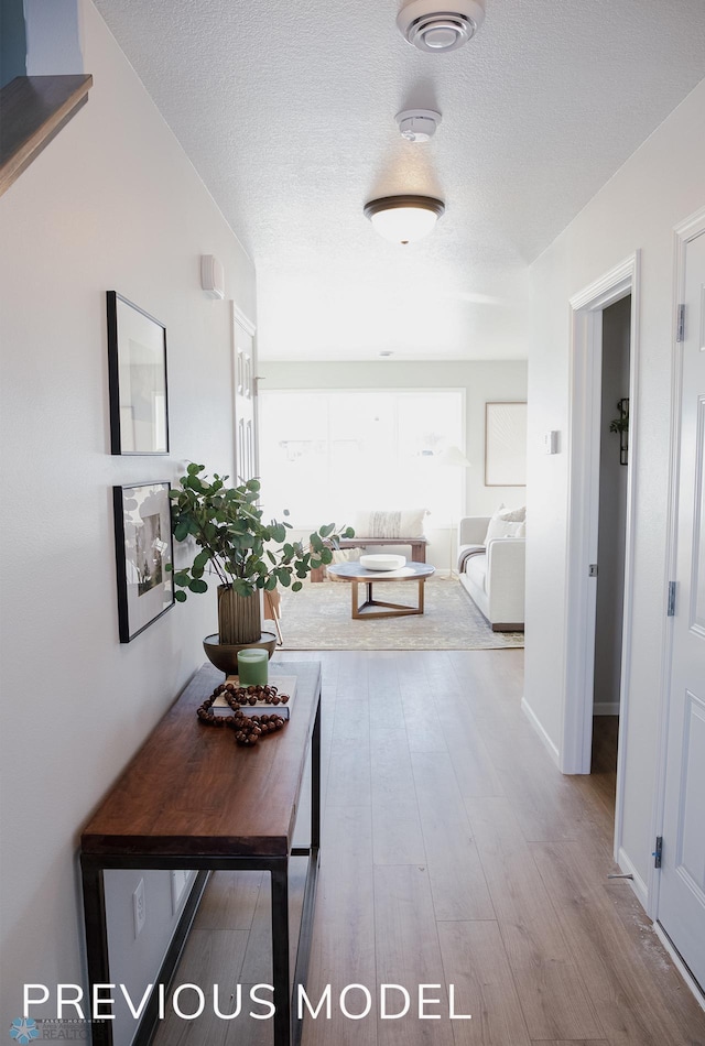 corridor featuring a textured ceiling and wood finished floors