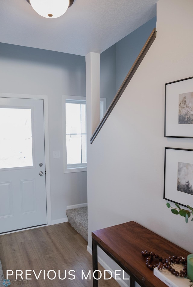 foyer featuring baseboards, stairs, and wood finished floors